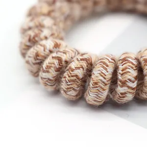 Close-up detail of vintage fabric wrapped telephone wire hair tie with woven texture.