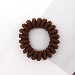 Brown telephone cord hair tie close-up, fabric wrapped elastic spiral hair band detail shot.