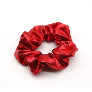 Red metallic hair scrunchie detail shot, glossy red hair tie accessory close up.