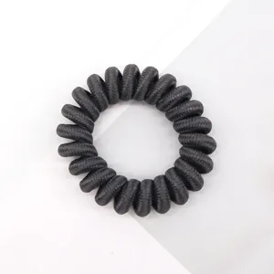 Black telephone wire hair tie detail, showing elastic texture and spiral shape close up.