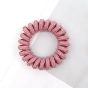 Detailed view of a pink fabric telephone wire hair tie, perfect for daily hairstyles.