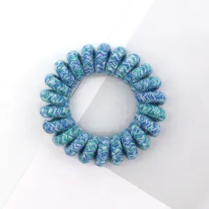 Close-up detail of blue and green woven spiral hair tie, showing delicate braided texture.