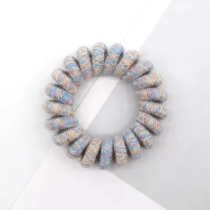 Detailed close-up of a multi-color woven spiral telephone wire hair tie with pastel texture.