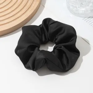 Close-up detail of a smooth black satin hair scrunchie, elegant daily hair accessory.