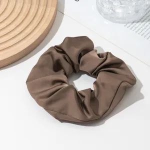 Brown satin hair scrunchie detail view, elegant ponytail tie accessory for women.