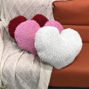 Close-up detail of soft heart-shaped fluffy chenille decorative pillow on cozy sofa.