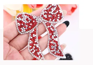 Close up of sparkling red and clear rhinestone bow patch detail, ideal for clothing and hats.