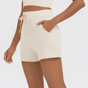 Detail view of beige high-waisted activewear shorts with side pockets and drawstring waist.