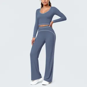 Detailansicht des blauen langärmligen Crop-Tops und der Schlag-Yogahose mit weißer Paspelierung.