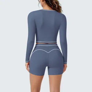 Back detail view of blue long sleeve crop top and shorts yoga set with white piping trim.