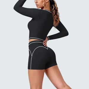 Detail view of black long sleeve yoga crop top and shorts with contrast piping design.