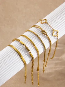Vue détaillée d'un ensemble de bracelets en acier titane doré avec trèfle et serpents.