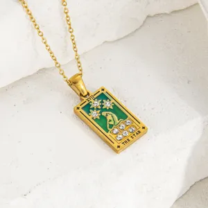 Primer plano detallado del collar de cartas de tarot doradas con esmalte verde y brillantes.