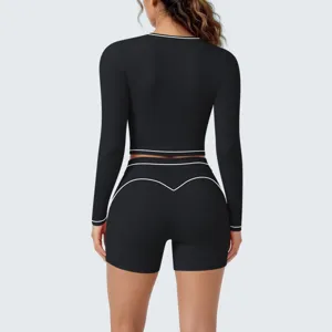 Black long sleeve crop top and high waist shorts yoga set with white contrast piping details.
