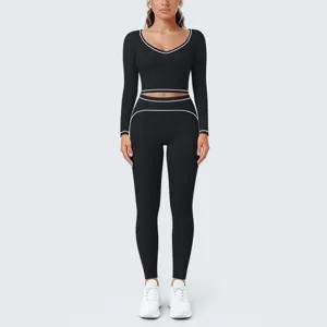 Detailed view of the black long-sleeve crop top and yoga leggings set with white contrast piping.