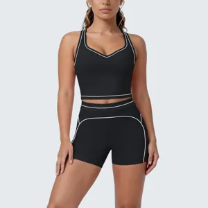 Black athletic two-piece yoga set with white contrast piping, featuring a crop top and shorts.