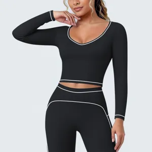 Gedetailleerd uitzicht op zwarte sport crop-top met lange mouwen en contrasterende bies.