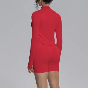 Detail view of the seamless red long-sleeve mock neck sports top and matching shorts set.