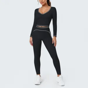 Detailed view of the sleek black long-sleeve crop top and matching leggings with white trim.