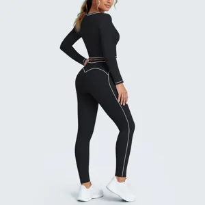 Detail view of black athletic long sleeve crop top and matching leggings with white contrast trim.