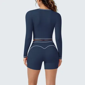 Close-up back view of dark blue activewear crop top and shorts set with white contrast piping.