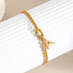 Detailansicht vergoldetes Schlangenkettenarmband mit Buchstabe A Anhänger und Knoten.