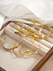 Goldener Edelstahl Knoten offener Armreif Set minimalistischer Modeschmuck Display.