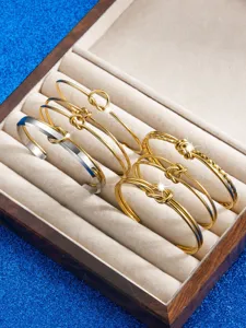 Edelstahl Knoten Armband Detail, goldene Manschette, minimalistischer Modeschmuck Display.