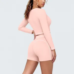 Detail shot of pink long sleeve activewear set with white piping, elastic yoga shorts.