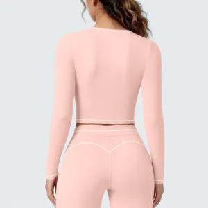 Roze sportcrop top met lange mouwen en contrasterende witte bies, ademend fitness detail.