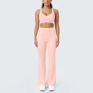 Set yoga rosa con profili a contrasto, top corto sportivo e pantaloni a zampa a vita alta.