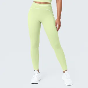 Primer plano detallado de mallas de yoga verdes de talle alto con ribetes blancos en contraste.