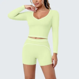 Detailed view of a light green long sleeve crop top and shorts yoga set with white piping.