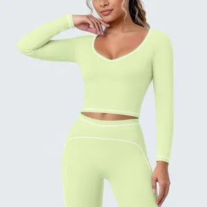 Detail van lichtgroene sport-croptop met lange mouwen en contrasterende witte bies.