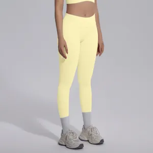 Close-up detail of seamless high-waisted yellow yoga leggings and sports bra, breathable fit.