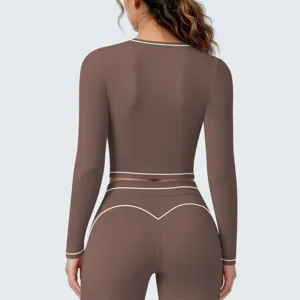 Detailansicht von braunem sportlichen Langarm-Oberteil und Leggings mit weißen Paspeln.