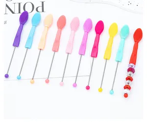 Close-up detail showing multi-color silicone blackhead and lip brushes with long metal handles.