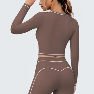 Gedetailleerd overzicht van de bruine crop top met lange mouwen en leggings met contrasterende bies.