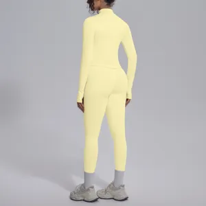 Vista posteriore dettaglio top sportivo a maniche lunghe e leggings da yoga tinta unita.