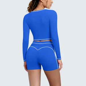 Close-up view of blue long sleeve crop top and shorts yoga set featuring white piping.