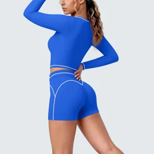 Detail view of women's blue activewear long sleeve top and shorts yoga set with white piping.