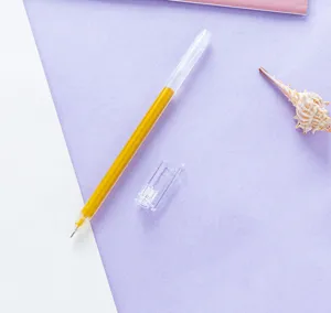 Primer plano detallado de un boligrafo de gel amarillo con cuerpo transparente y tapa sobre fondo claro.