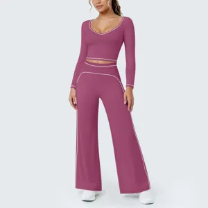 Details des bordeauxroten Langarm-Crop-Tops und der weiten Yogahose mit weißem Paspel.