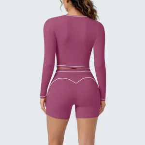 Detail view of women's long-sleeve crop top and shorts yoga set with contrast piping.