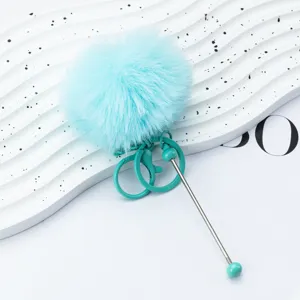 Blue fluffy pom pom keychain with green metal ring and pendant for bags or keys decor.