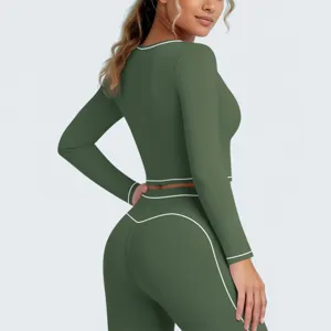 Groene sportset met lange mouwen, crop top en legging met opvallende contraststiksels.