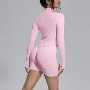 Back view of women seamless solid pink long sleeve athletic top and fitness shorts set.