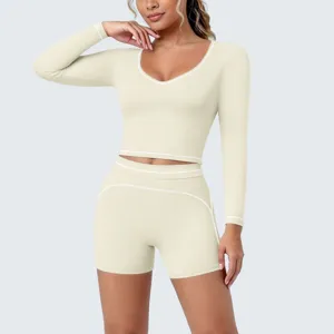 Details of the beige long-sleeve crop top and shorts yoga set featuring contrast white piping.