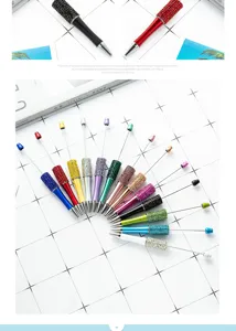 Detailed view of colorful rhinestone DIY beadable pens arranged neatly on grid background.