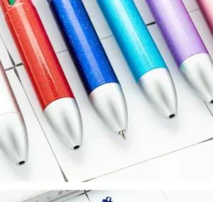 Primer plano detallado de bolígrafos retráctiles brillantes de colores sobre papel cuadriculado.